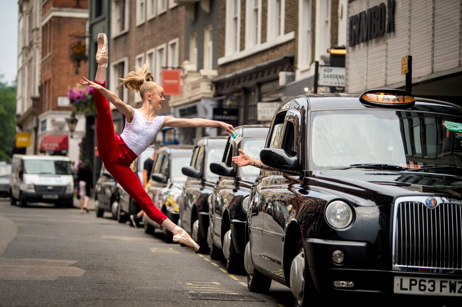 Dancer leaping while paying a London black cab driver