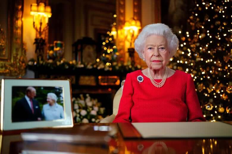 Queen Elizabeth II seated behind her desk with a Christmas tree in the background