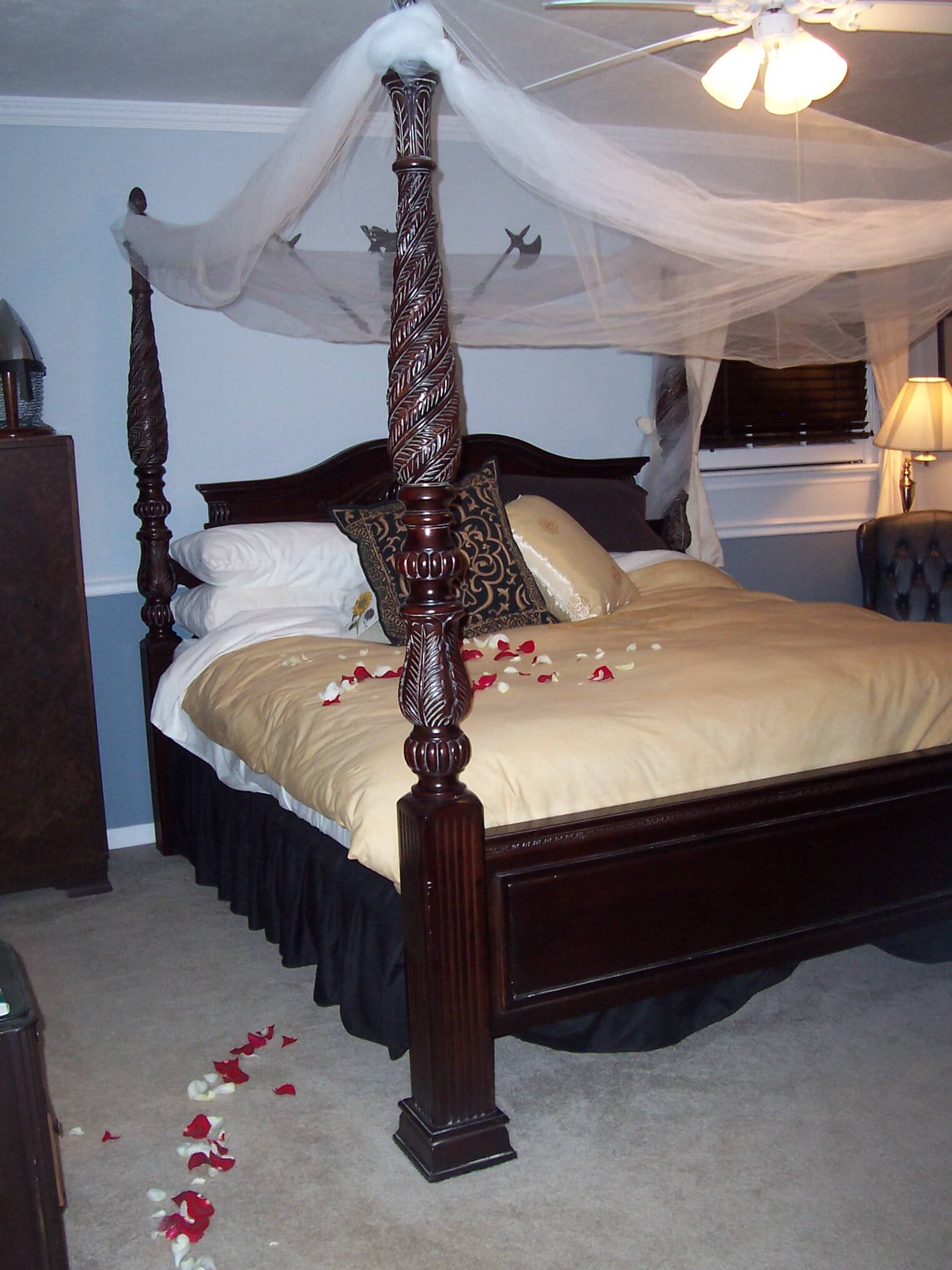 Four poster bed with rose petals and white tulle